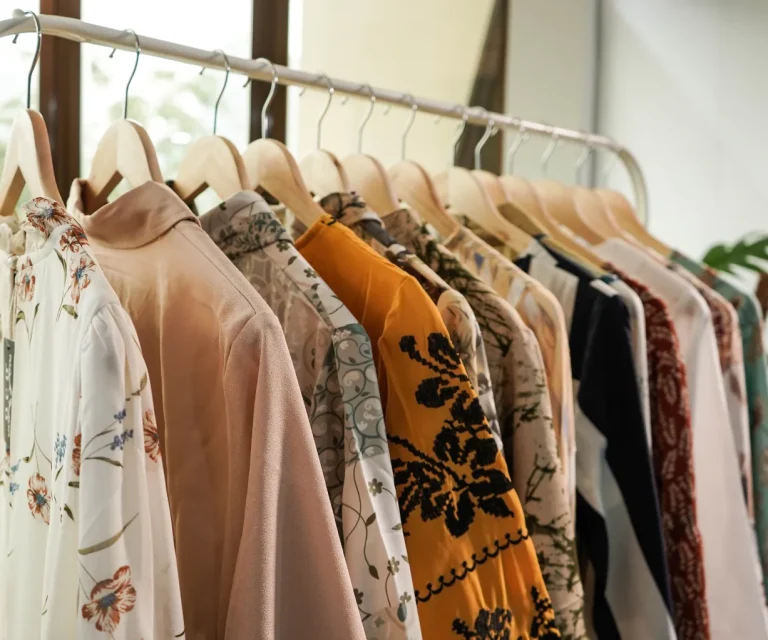 Rack of stylish women's blouses on wooden hangers.