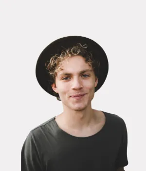 Young man with curly hair wearing a black hat and gray shirt